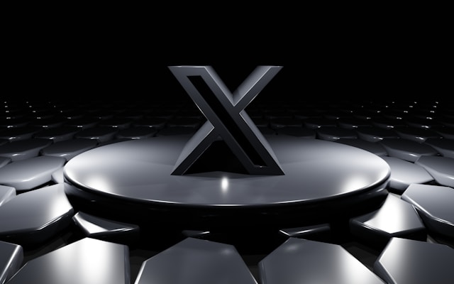 A sleek, black "X" symbol standing on a circular platform with a futuristic, reflective surface. 