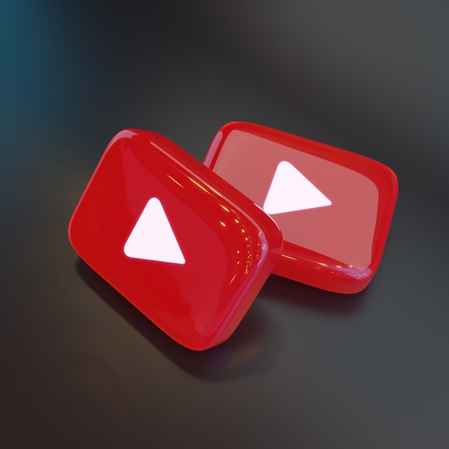 Two glossy 3D YouTube play button icons in red with white triangles, set against a dark background.