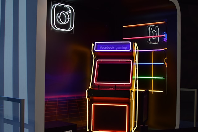 A neon-lit arcade machine with 'Facebook Gaming' logo, surrounded by colorful lights and Instagram logos.