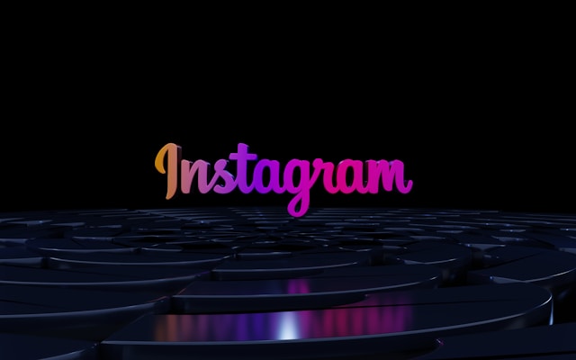 The Instagram logo in gradient colors on a dark, reflective surface.